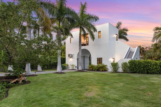 back house at dusk with a lawn