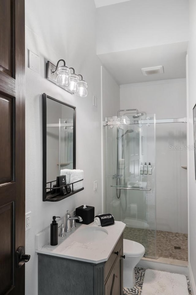 bathroom featuring tile patterned floors, vanity, toilet, and walk in shower