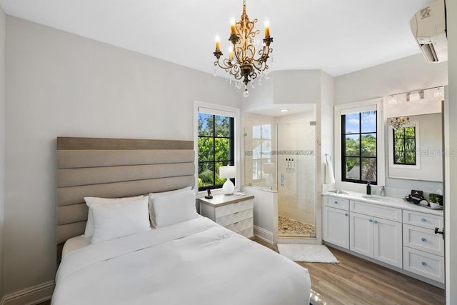 bedroom featuring light wood-type flooring, multiple windows, a wall mounted AC, and ensuite bath