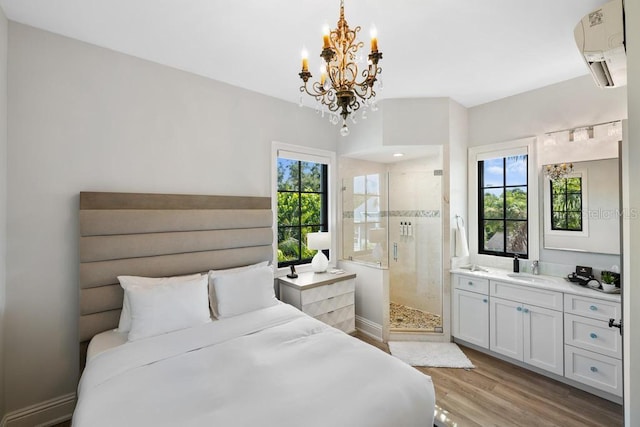 bedroom with ensuite bathroom, sink, light hardwood / wood-style floors, and a wall unit AC