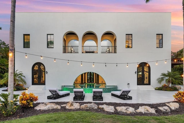 back house at dusk with a patio area and french doors