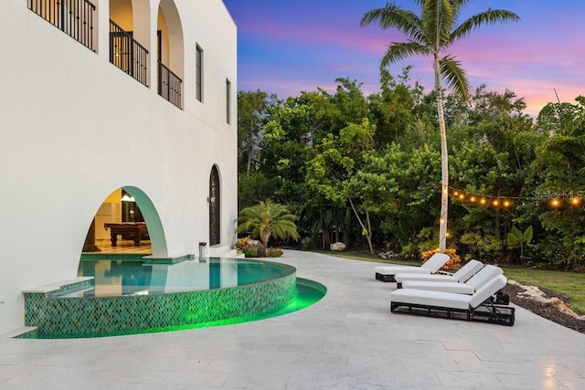 pool at dusk featuring a patio area