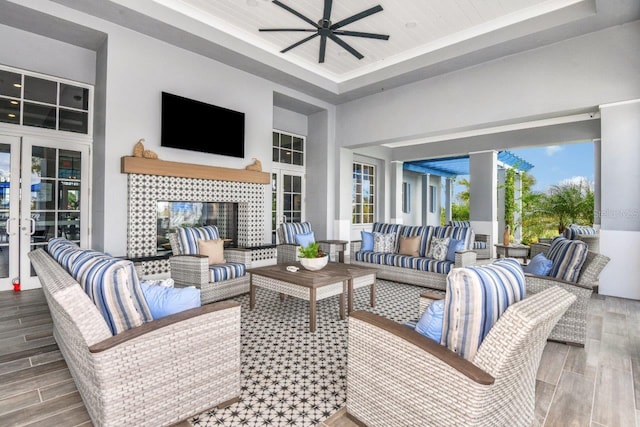 interior space with hardwood / wood-style flooring, ceiling fan, a tray ceiling, french doors, and a towering ceiling