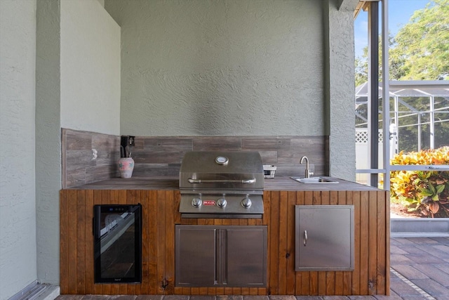 view of patio featuring area for grilling, sink, glass enclosure, and a grill