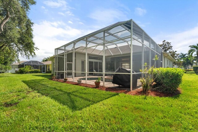 back of property featuring a lanai and a lawn