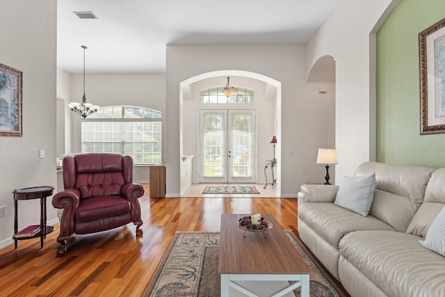 living room with light hardwood / wood-style flooring, a chandelier, and french doors