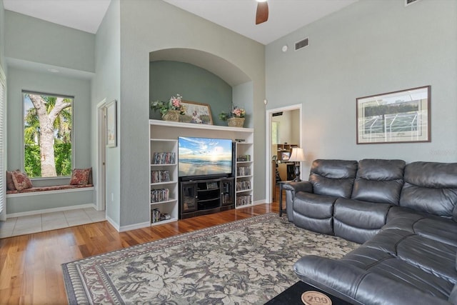 living room with wood-type flooring, high vaulted ceiling, and ceiling fan