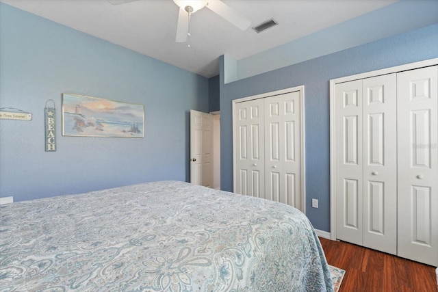 bedroom with two closets, ceiling fan, and dark hardwood / wood-style floors