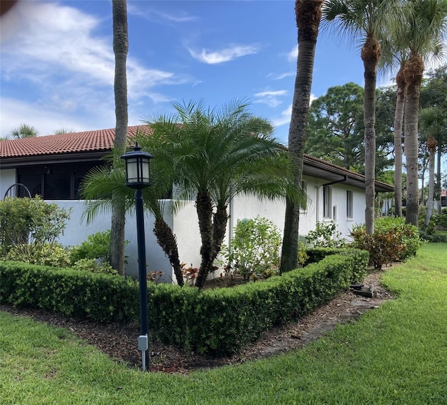 view of side of property with a tile roof, a lawn, and stucco siding