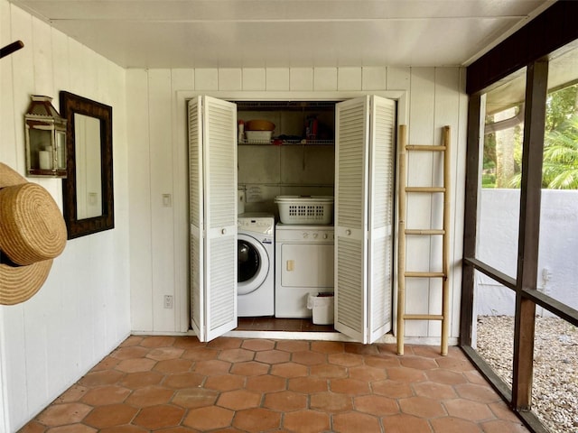 clothes washing area with washer and clothes dryer and wood walls