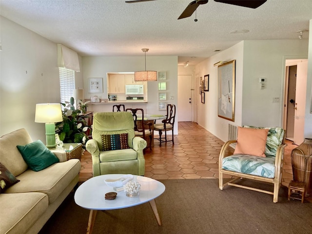 living room featuring tile patterned floors, ceiling fan, and a textured ceiling