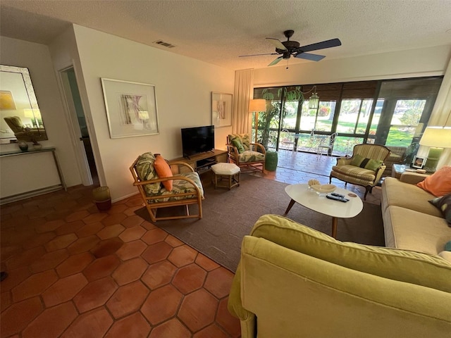 living room with ceiling fan, dark tile patterned flooring, and a textured ceiling