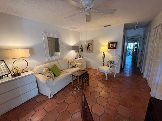 unfurnished living room with ceiling fan, dark tile patterned flooring, and a textured ceiling