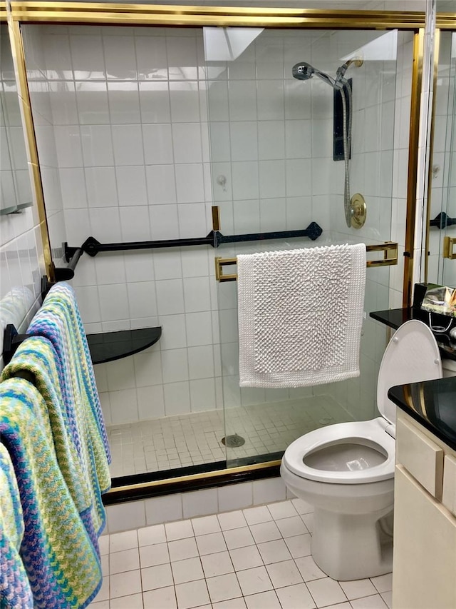 bathroom with vanity, tile walls, tile patterned flooring, toilet, and a shower with shower door