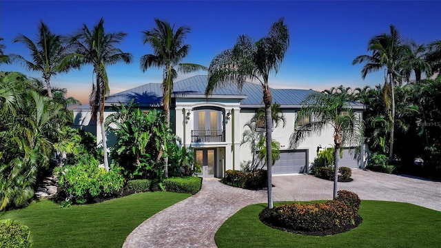 view of front of property with a balcony, a lawn, and a garage