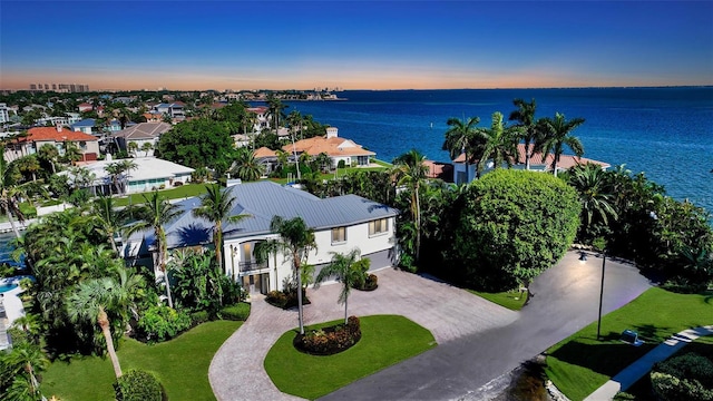 aerial view at dusk featuring a water view and a residential view