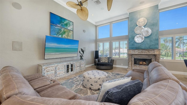 living room featuring a high ceiling, a fireplace, tile patterned flooring, crown molding, and ceiling fan