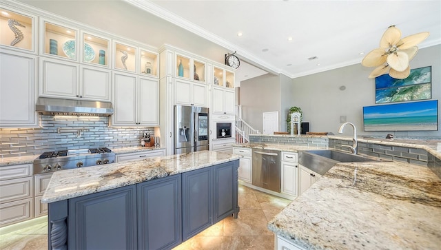 kitchen featuring light stone countertops, appliances with stainless steel finishes, a center island, sink, and white cabinetry