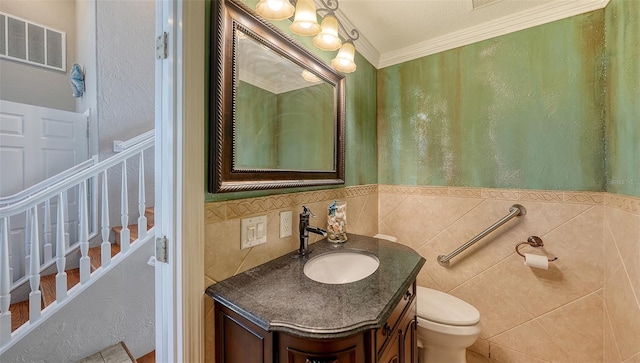 bathroom with crown molding, vanity, toilet, and tile walls