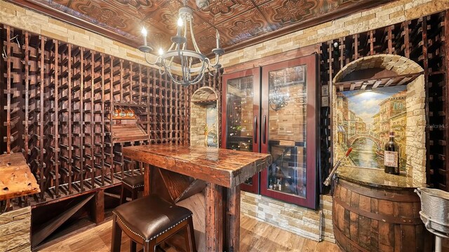 wine area featuring hardwood / wood-style flooring and a notable chandelier