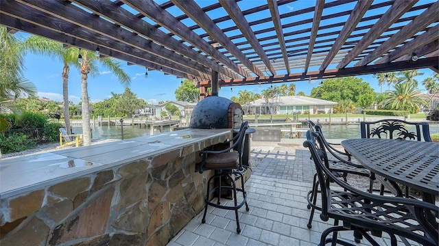 view of patio featuring a pergola, a water view, and a bar