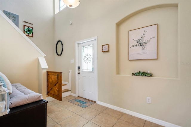 foyer entrance with light tile patterned floors, plenty of natural light, stairway, and baseboards