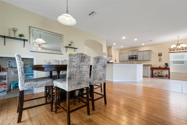 dining room featuring arched walkways, a notable chandelier, recessed lighting, visible vents, and light wood-style floors