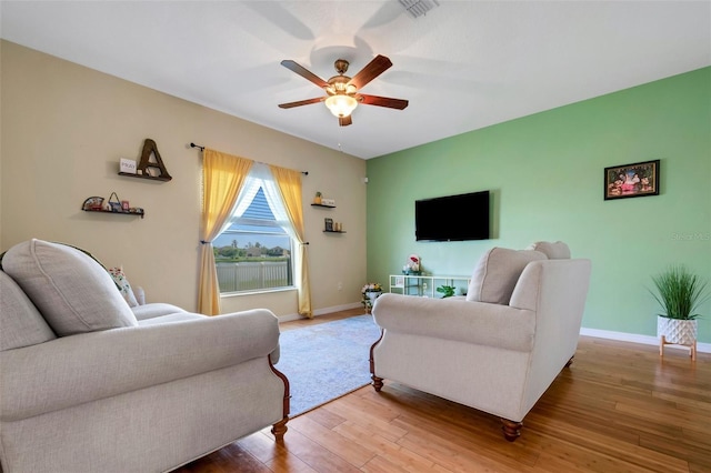 living room with ceiling fan, visible vents, baseboards, and wood finished floors