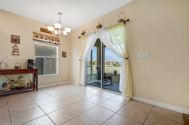 spare room with baseboards, light tile patterned flooring, and an inviting chandelier