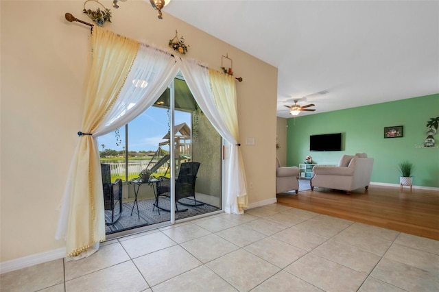 interior space featuring a ceiling fan, baseboards, and light tile patterned floors