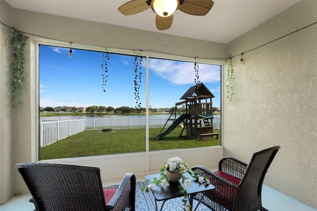 sunroom / solarium featuring a water view, a ceiling fan, and a wealth of natural light