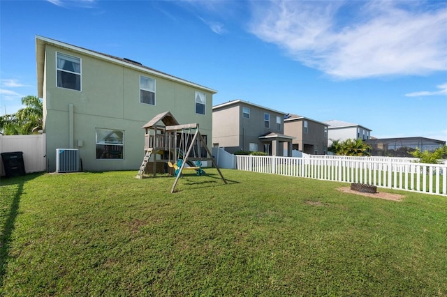 back of property with a yard, a playground, a fenced backyard, and central air condition unit