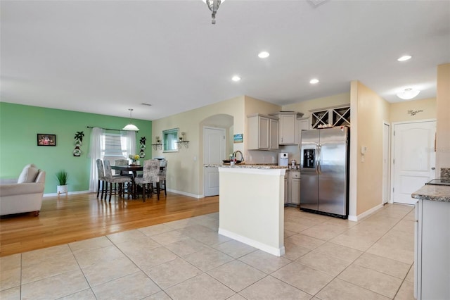 kitchen with light stone counters, recessed lighting, hanging light fixtures, light tile patterned flooring, and stainless steel fridge