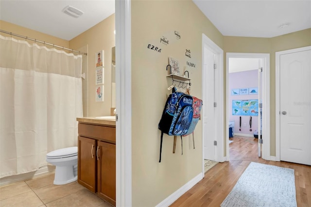 bathroom featuring baseboards, visible vents, toilet, wood finished floors, and vanity