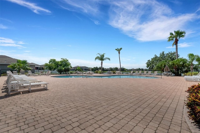 community pool with a patio area and fence