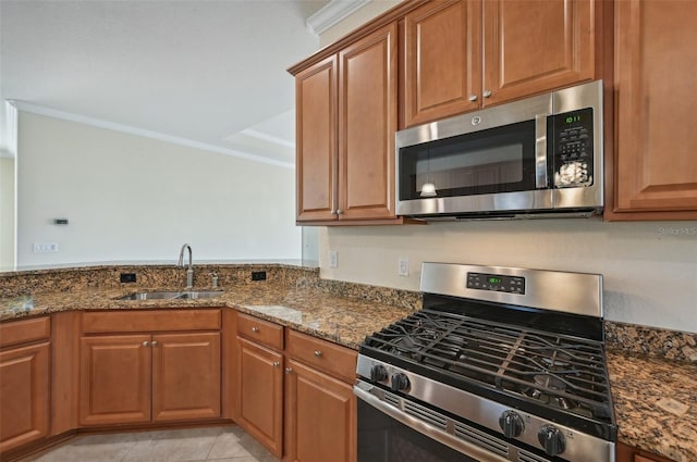 kitchen with sink, ornamental molding, dark stone counters, and appliances with stainless steel finishes