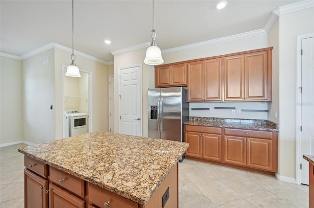 kitchen with a center island, stainless steel fridge, washer / dryer, and decorative light fixtures