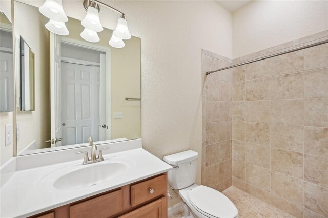 bathroom with tiled shower, vanity, toilet, and a notable chandelier