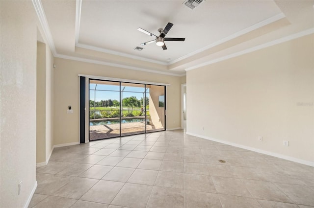 tiled empty room with ceiling fan, ornamental molding, and a raised ceiling