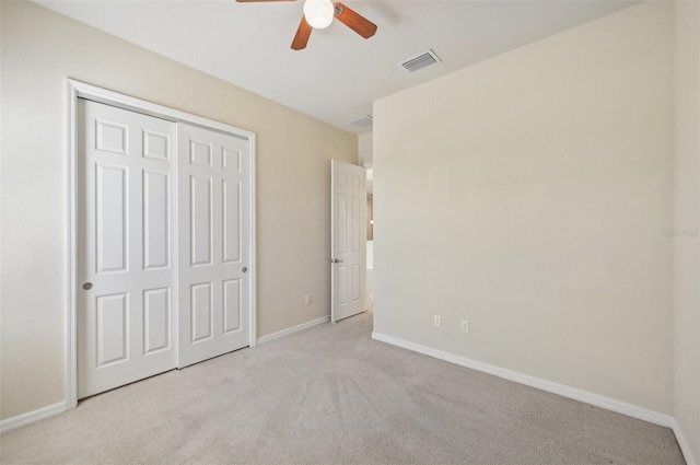 unfurnished bedroom with ceiling fan, light colored carpet, and a closet