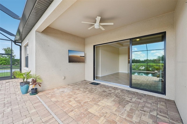 view of patio / terrace featuring glass enclosure, ceiling fan, and a water view