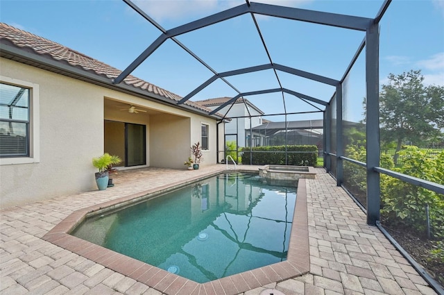 view of pool featuring ceiling fan, a patio area, glass enclosure, and an in ground hot tub