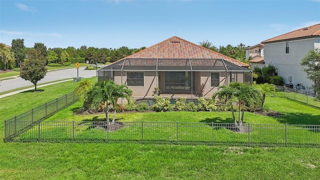 rear view of house featuring glass enclosure and a lawn