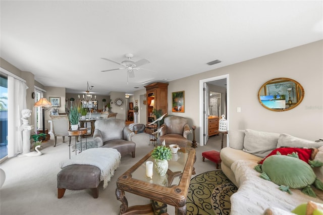 carpeted living room with ceiling fan with notable chandelier