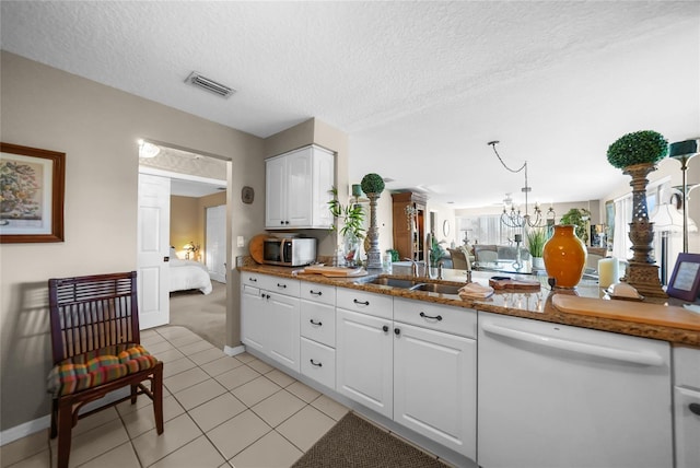 kitchen with white cabinets, white dishwasher, light tile patterned floors, a textured ceiling, and a chandelier