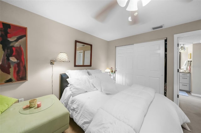 carpeted bedroom featuring ensuite bathroom, ceiling fan, and a closet