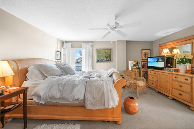 bedroom featuring a textured ceiling, light colored carpet, and ceiling fan