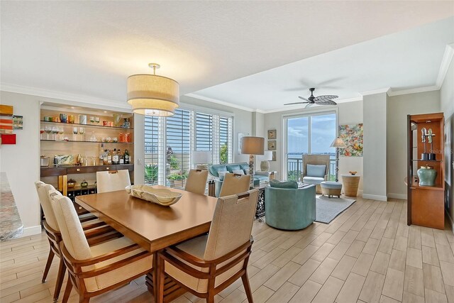 dining room with built in features, ceiling fan, light wood-type flooring, and crown molding