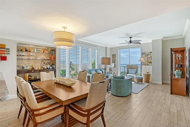 dining space with ceiling fan, ornamental molding, and light wood-type flooring