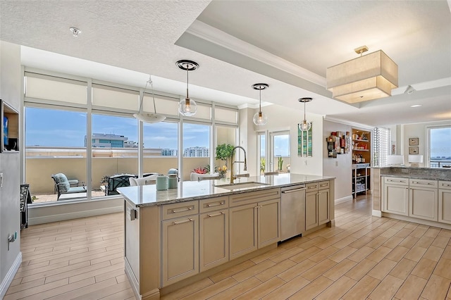 kitchen with hanging light fixtures, cream cabinetry, sink, dishwasher, and a kitchen island with sink